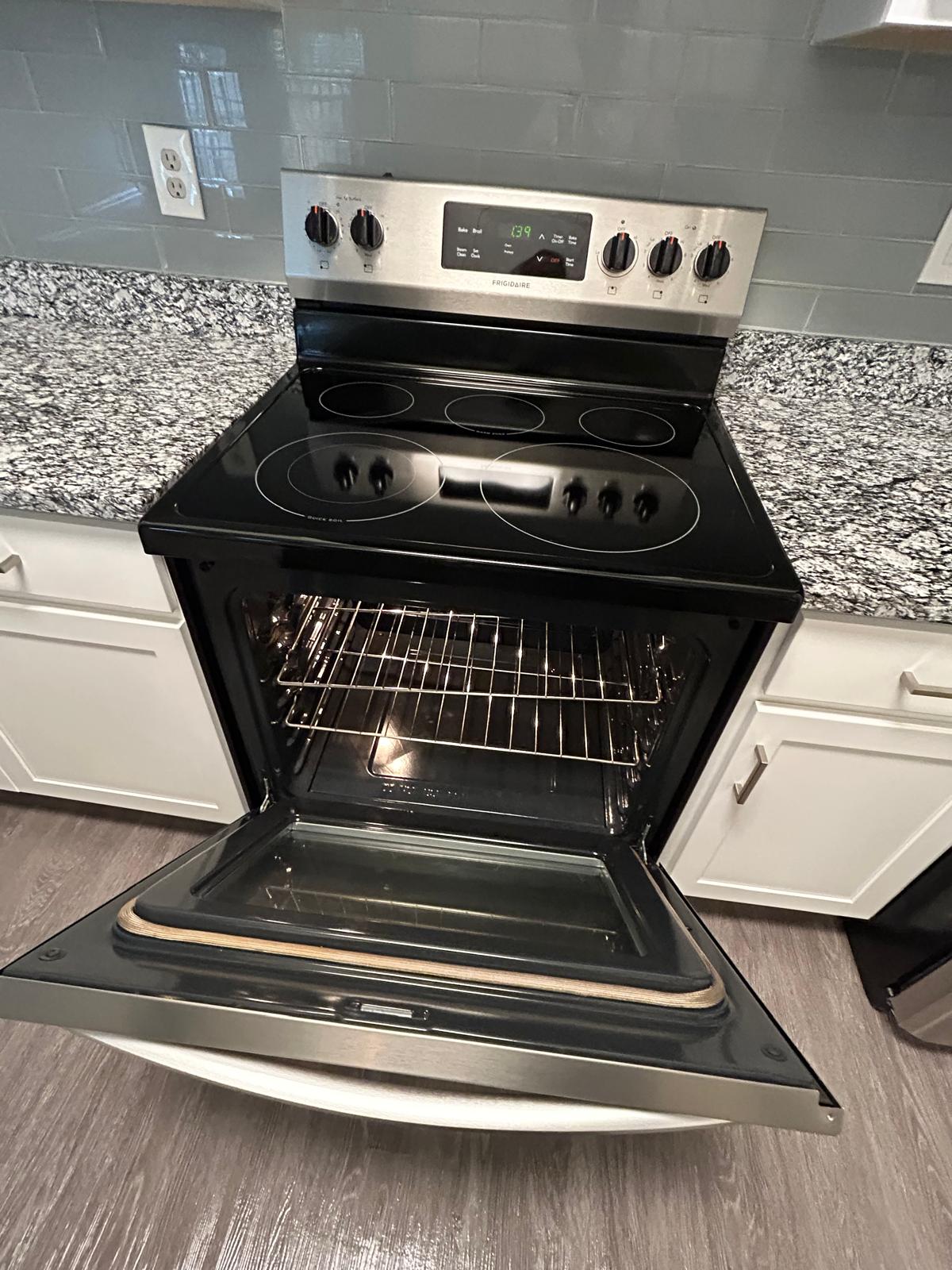 Polished electric stove and open oven after deep cleaning